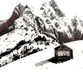 small mountain hut against snowy alpine peaks